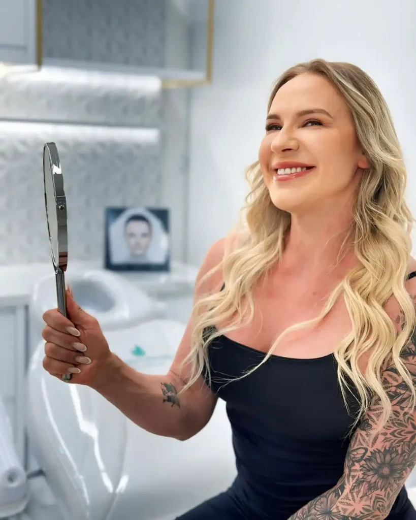 Mulher sorrindo enquanto se olha no espelho após procedimento de harmonização facial em clínica estética de Curitiba
